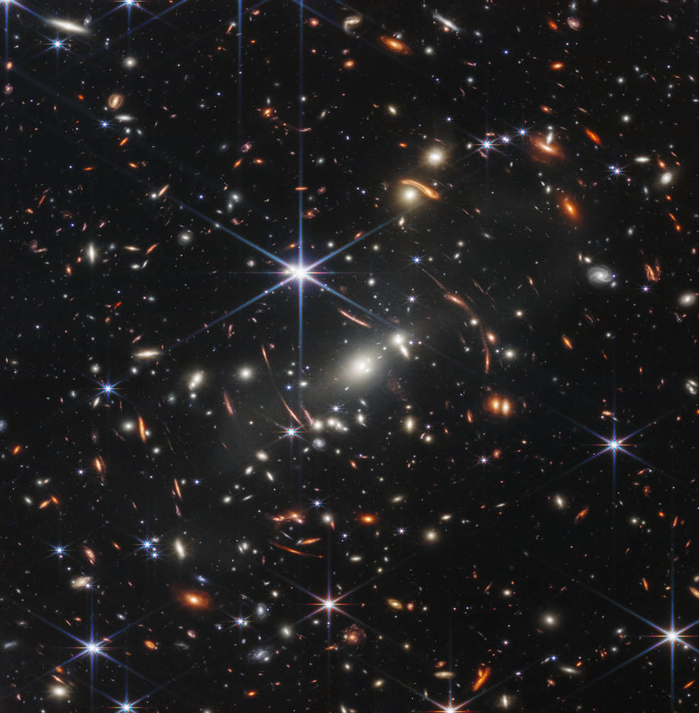 銀河団「SMACS 0723」を赤外線カメラで複数回撮影して合成し、疑似カラー化したもの。画角は、人間が手を伸ばした指先に載せた砂粒ほどと極めて狭いにもかかわらず、数千個もの銀河が捉えられているそうだ。一部銀河の形が歪んでいるのは、強大な銀河団の質量で生じた重力レンズの影響（出典：NASA）