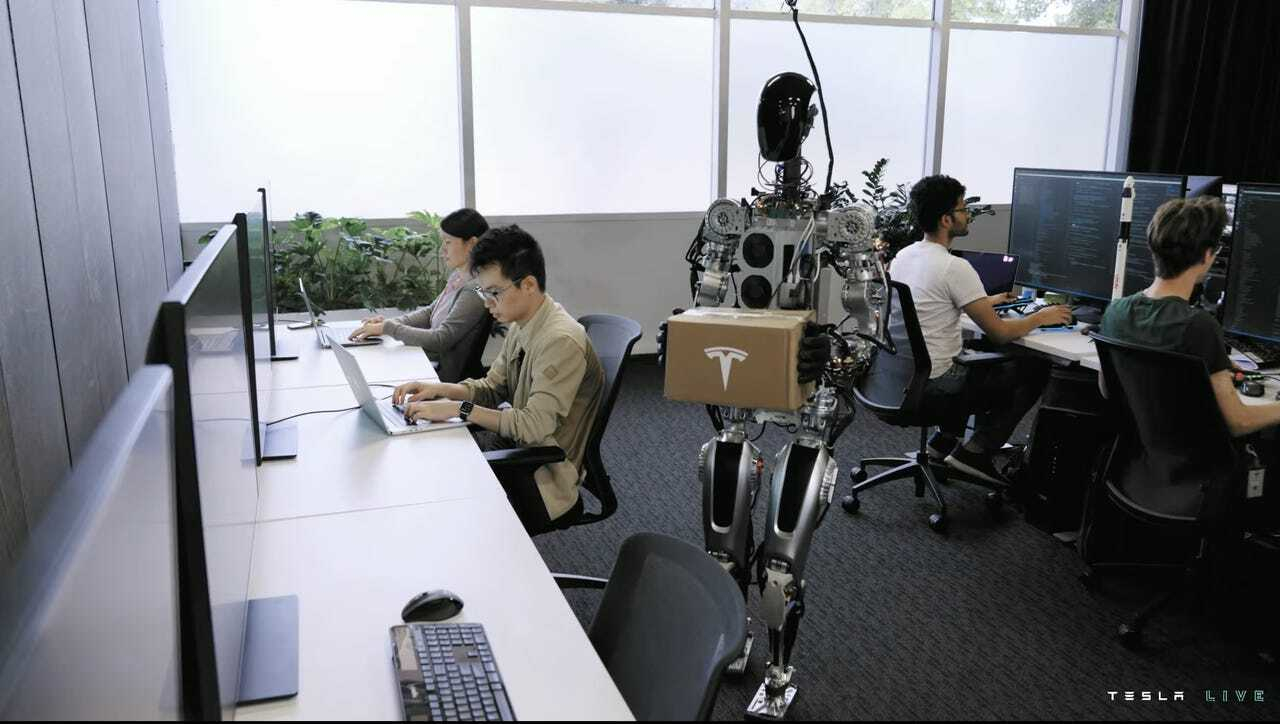 Teslaの人型ロボットOptimusが荷物を持ってオフィスを歩いている（出典：Tesla）